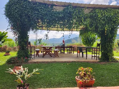 a pergola with tables and chairs in a garden at Finca la India Cerro Tusa in Tarso