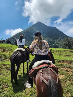two people riding on horses in a field at Finca la India Cerro Tusa in Tarso