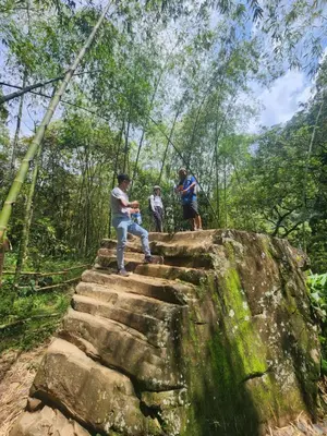 a group of people sitting on a rock in the forest at Finca la India Cerro Tusa in Tarso