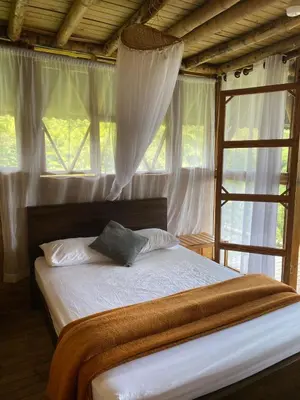a bedroom with a bed with white sheets and a window at Glamping Falan Tolima in Falan