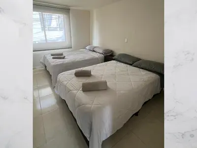 two beds in a room with a window at Casa amoblada 15 personas 6 habitaciones 4 baños - Frente al terminal y cable aereo, Cerca de Expoferias, Bosque Popular y Termales del Otoño in Manizales