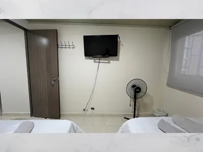 a room with two beds and a flat screen tv at Casa amoblada 15 personas 6 habitaciones 4 baños - Frente al terminal y cable aereo, Cerca de Expoferias, Bosque Popular y Termales del Otoño in Manizales