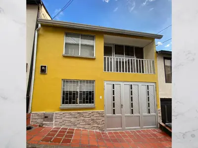 a yellow house with two gray garage doors at Casa amoblada 15 personas 6 habitaciones 4 baños - Frente al terminal y cable aereo, Cerca de Expoferias, Bosque Popular y Termales del Otoño in Manizales