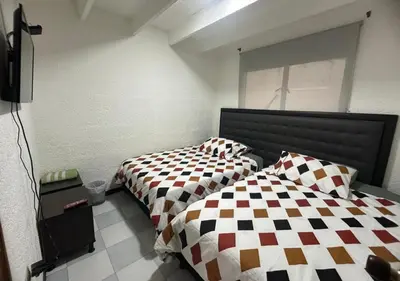 a bedroom with two beds and a television in it at Hospedaje Gladys in Manizales