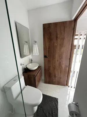 a bathroom with a toilet and a sink and a wooden door at Alojamiento Privado en Avenida Principal in Manizales