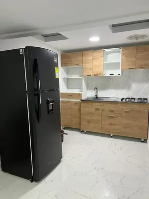 a kitchen with a black refrigerator and wooden cabinets at Alojamiento Privado en Avenida Principal in Manizales