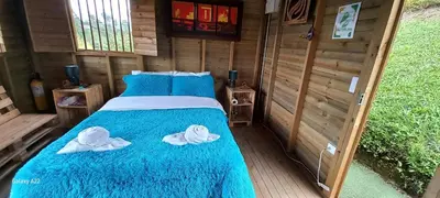 a bed in a wooden room with two hats on it at Entre Colinas Lodge in El Peñol