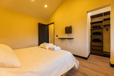a bedroom with a white bed and a yellow wall at Villa Kobus in San Antonio de Pereira