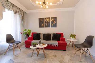 a living room with a red couch and two chairs at Great family home near the stadium and beautiful neighborhood in Medellín