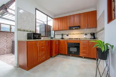 a kitchen with wooden cabinets and a large window at Great family home near the stadium and beautiful neighborhood in Medellín
