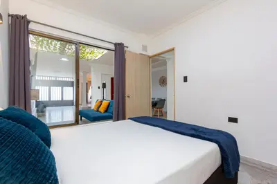 a bedroom with a white bed and a large window at Great family home near the stadium and beautiful neighborhood in Medellín