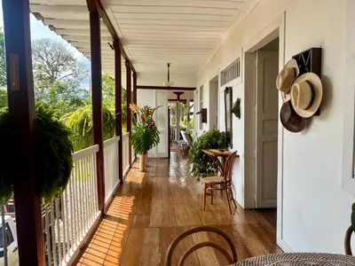 a porch with chairs and a table on a house at Hacienda El Rosario Manizales in Manizales