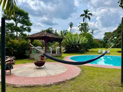 a hammock in a yard next to a pool at Hacienda El Rosario Manizales in Manizales