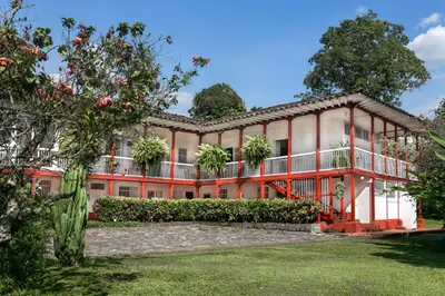 an exterior view of a large building with trees at Hacienda El Rosario Manizales in Manizales