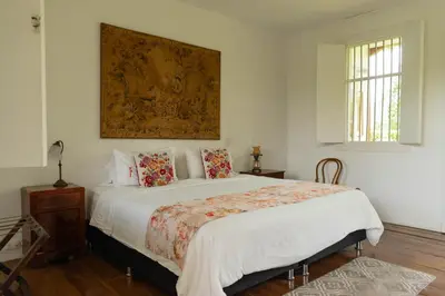 a bedroom with a large white bed with a painting on the wall at Hacienda El Rosario Manizales in Manizales