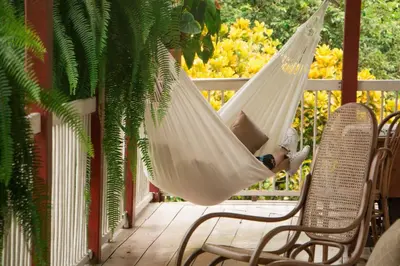 a person laying in a hammock on a porch at Hacienda El Rosario Manizales in Manizales