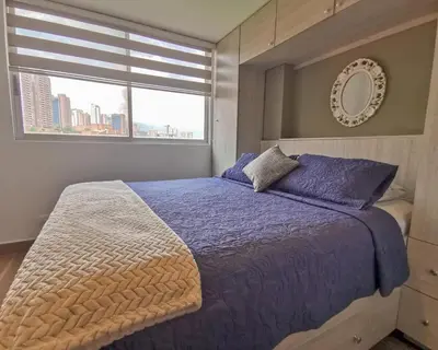 a bedroom with a bed with purple sheets and a window at Amazing view - Poblado in Medellín