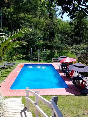 a swimming pool with tables and umbrellas and chairs at Casa Verano la rumbita Naturaleza, Piscina y Rio in Santa Fe de Antioquia