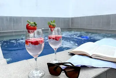 two wine glasses with strawberries in them next to a swimming pool at Hotel 79 Poblado in Medellín