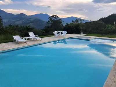 a pool with chairs and a table and mountains at lujosa villa campestre in Girardota