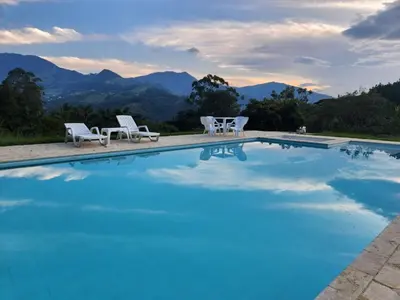 a swimming pool with chairs and mountains in the background at lujosa villa campestre in Girardota