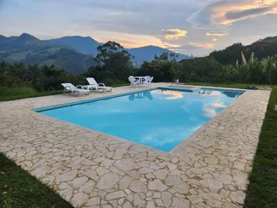 a swimming pool with chairs and a table and mountains at lujosa villa campestre in Girardota