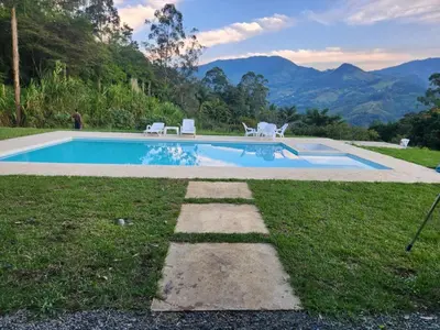 a swimming pool with chairs and mountains in the background at lujosa villa campestre in Girardota