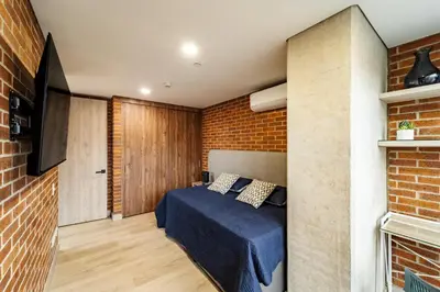 a bedroom with a bed and a brick wall at MEDELLIN LAURELES POR DÁS in Medellín