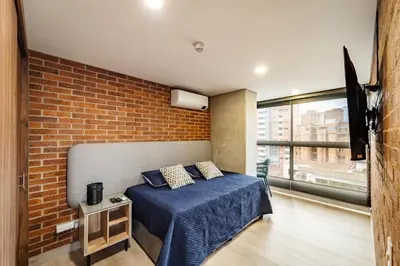 a bedroom with a bed and a brick wall at MEDELLIN LAURELES POR DÁS in Medellín