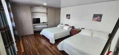 a hotel room with two beds and a television at Tu casa en Laureles in Medellín