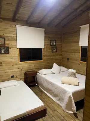 two beds in a wooden room with a window at Cabaña de cuento in Horizonte