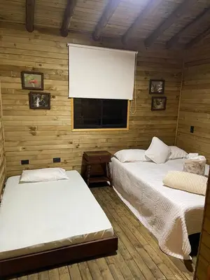 two beds in a wooden room with a window at Cabaña de cuento in Horizonte