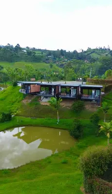 a house on a hill next to a pond at Suites del Lago in Marinilla