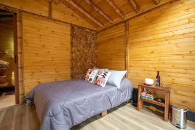 a bedroom with a bed and a wooden wall at KITE KIWE LODGE - Parque Arvi in Guarne