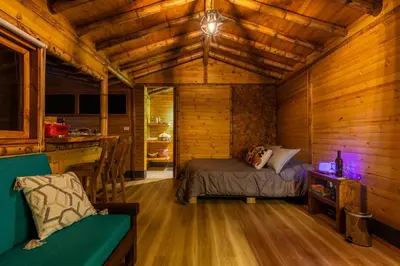 a bedroom with a bed in a wooden cabin at KITE KIWE LODGE - Parque Arvi in Guarne