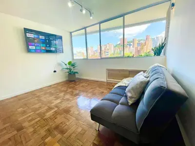 a living room with a couch and a large window at In the center of Poblado in Medellín