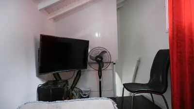 a living room with a flat screen tv and two chairs at Casa La Palma Habitación Altillo in Medellín