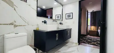 a bathroom with a toilet and a sink and a mirror at Moderno-Central El Poblado Apartamento in Medellín