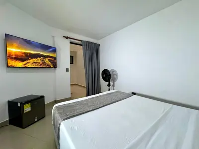 a bedroom with a bed and a tv on the wall at Praga Room Unicentro in Medellín