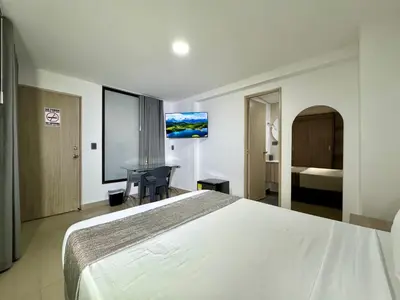 a hotel room with a large bed and a desk at Praga Room Unicentro in Medellín