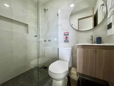 a bathroom with a toilet and a shower and a mirror at Praga Room Unicentro in Medellín