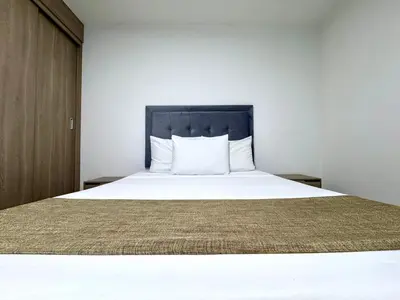 a bedroom with a white bed with a black headboard at Praga Room Unicentro in Medellín