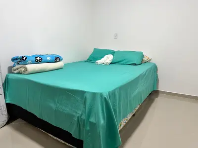 a bed with a green blanket and pillows on it at Lorena Apartamento in El Peñol