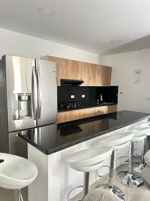 a kitchen with a stainless steel refrigerator and stools at Lorena Apartamento in El Peñol