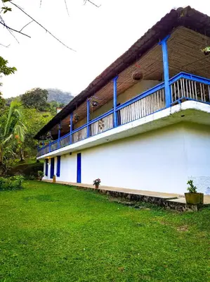 a building with a blue balcony and a green yard at Finca Rústica, Cocorná - Cacao, Charcos y Cascadas in Cocorná