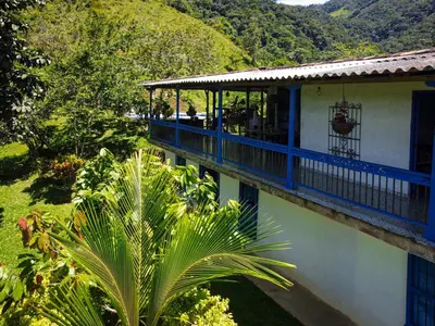 a house with a blue balcony and a palm tree at Finca Rústica, Cocorná - Cacao, Charcos y Cascadas in Cocorná
