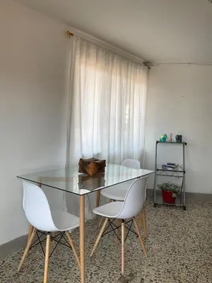 a glass table and two white chairs in a room at Apartamento cómodo en Medellín in Medellín