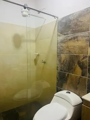 a bathroom with a toilet and a glass shower at Hermosa Casa de descanso Villa María in Don Matías