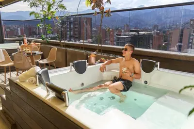 a man sitting in a hot tub on a rooftop at Stadio Aparta-Suite Bliss Rosa Negra in Medellín
