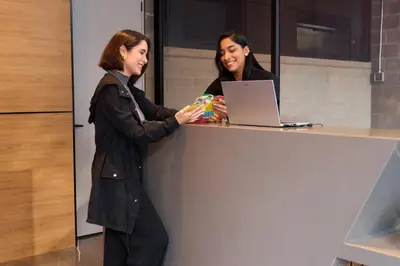 two women standing at a counter with a laptop at Stadio Aparta-Suite Bliss Rosa Negra in Medellín